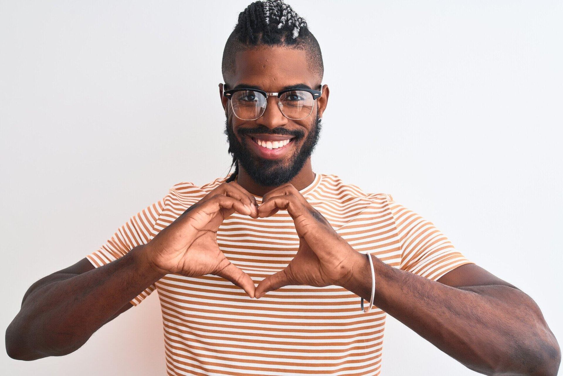 A man wearing glasses is making a heart shape with his hands.