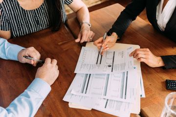 A group of people are sitting around a table looking at papers.