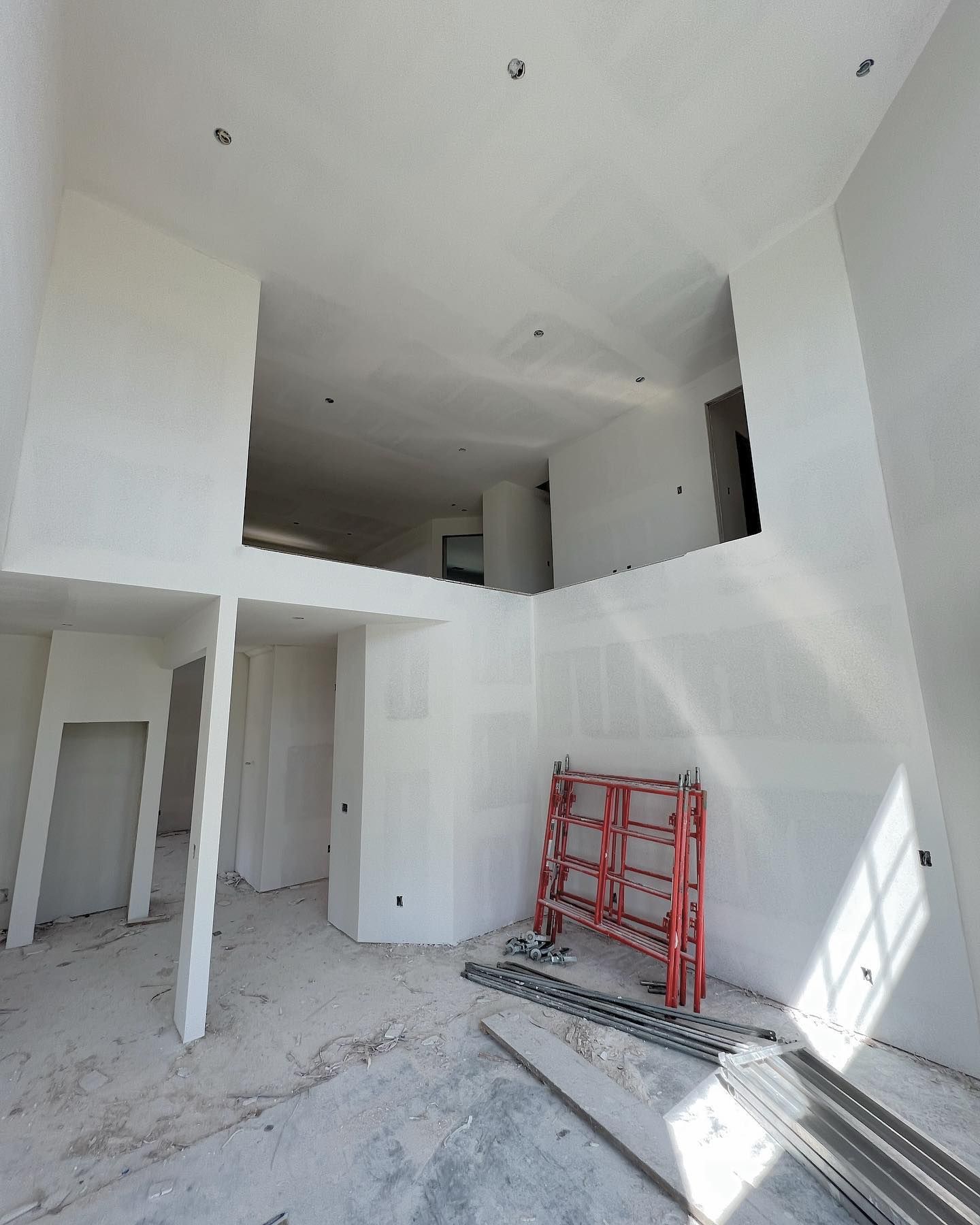 Interior under construction with white walls, exposed ceiling, and scaffolding.