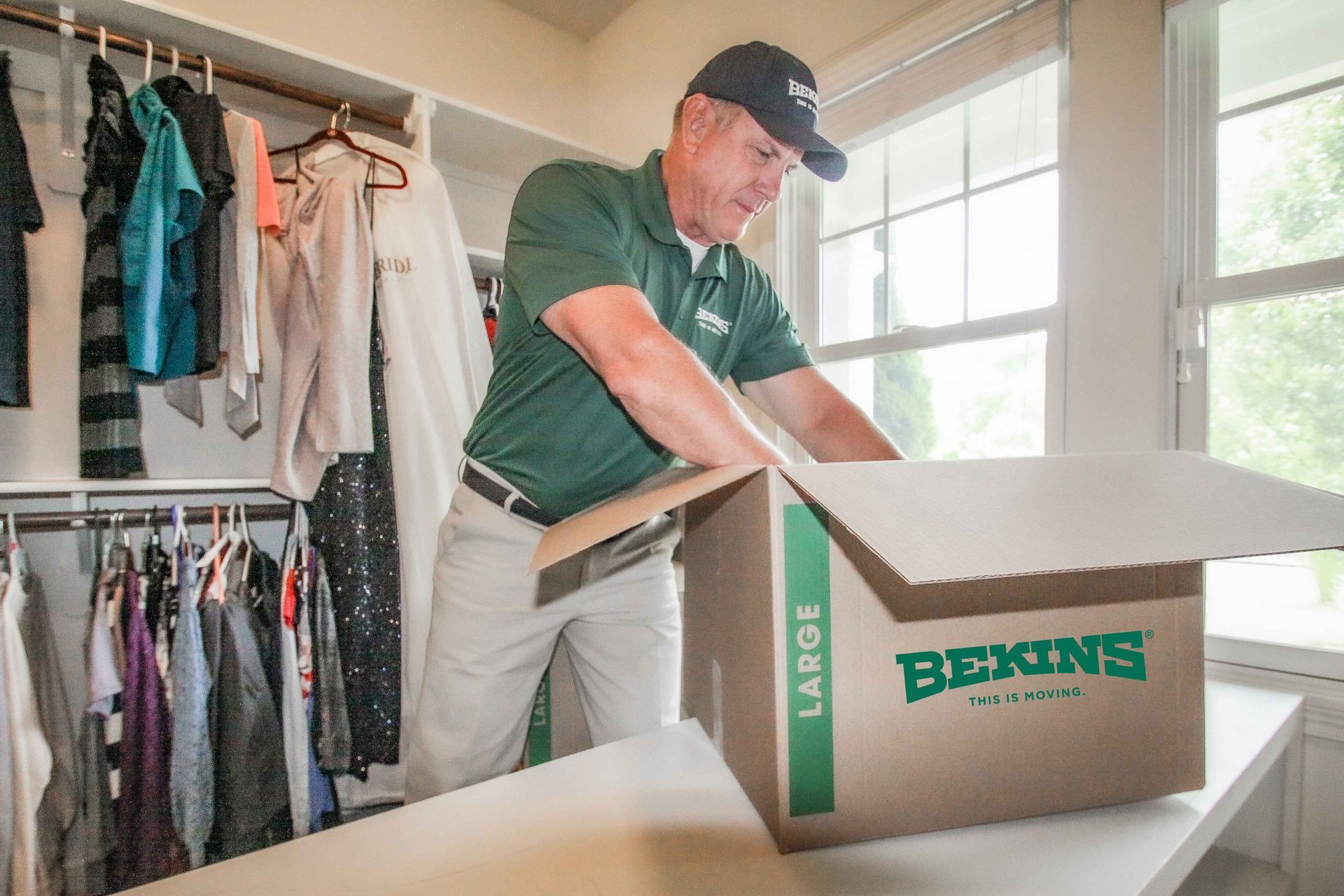 A man is packing a large box in a closet.