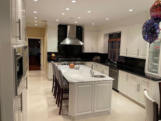 A large kitchen with white cabinets and black counter tops