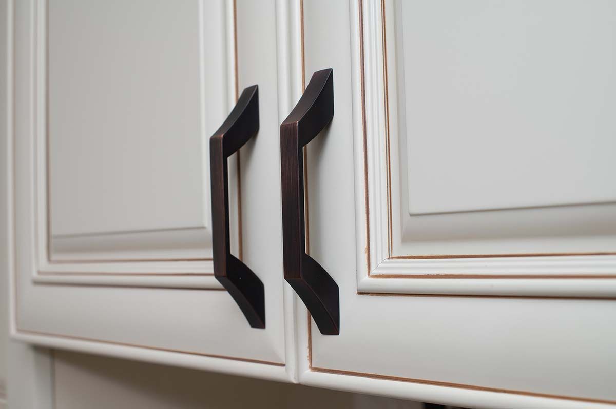 A close up of a white cabinet with black handles.