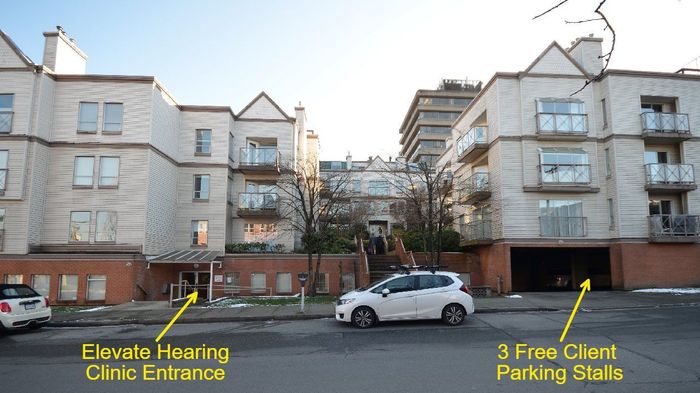 A white car is parked in front of a building that says elevate hearing clinic entrance