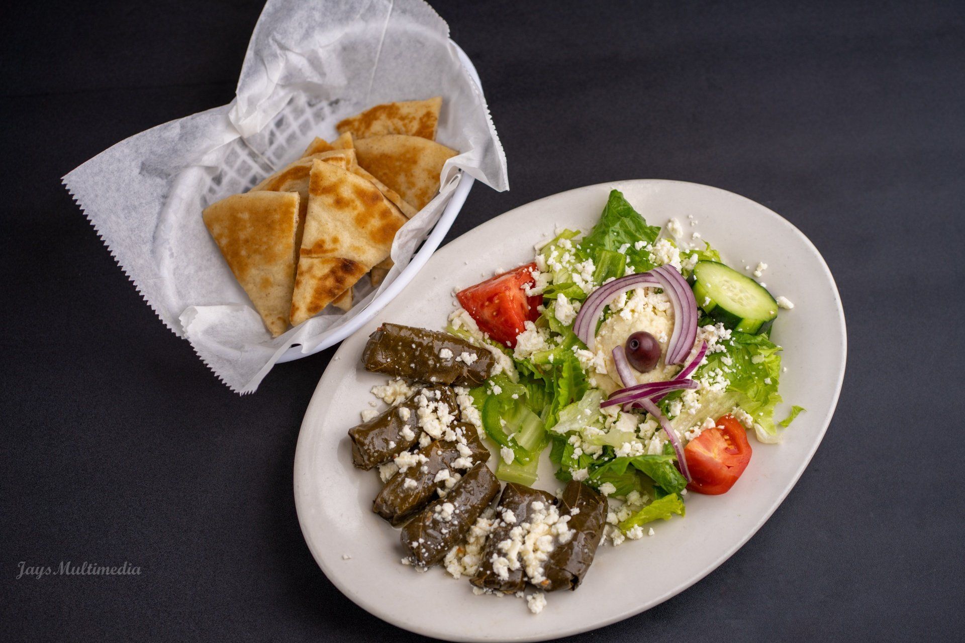 A plate of food with a basket of pita bread next to it.