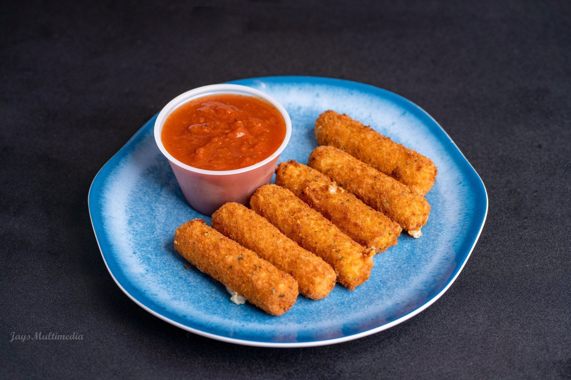 A blue plate topped with mozzarella sticks and dipping sauce.