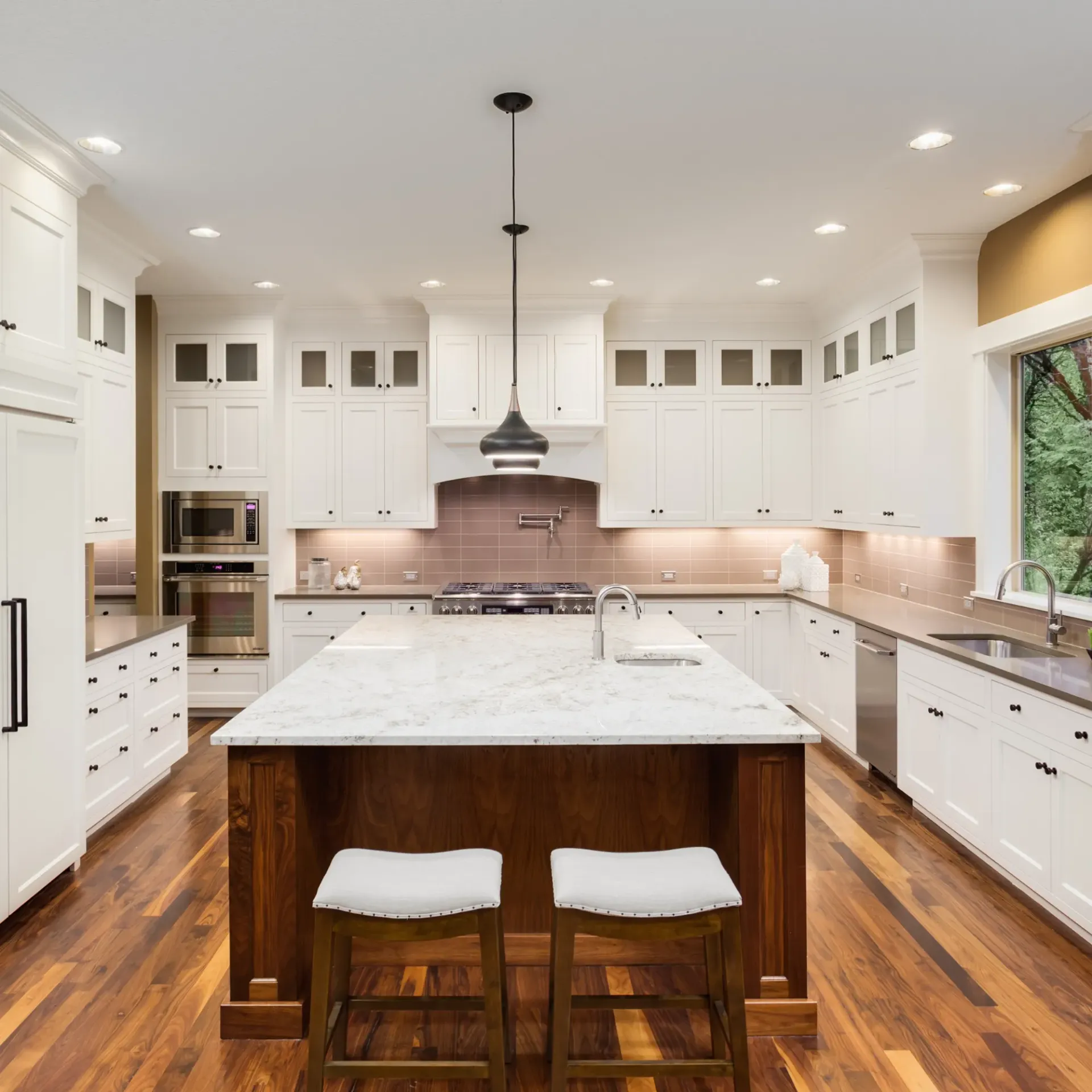 Sanchez Electric and Remodeling - A kitchen with white cabinets and a large island in the middle