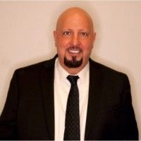 A bald man with a beard is wearing a suit and tie.
