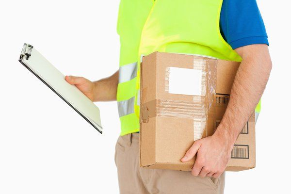 A delivery man is holding a box and a clipboard