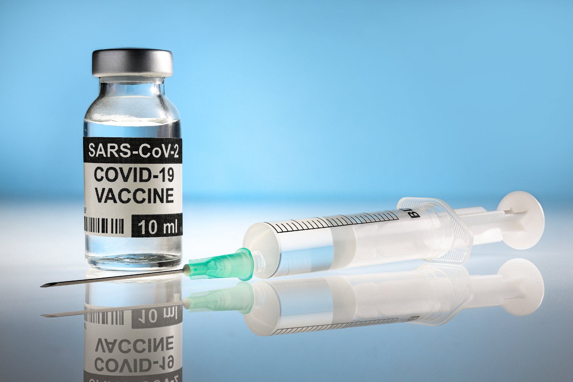 A bottle of covid-19 vaccine and a syringe on a table.