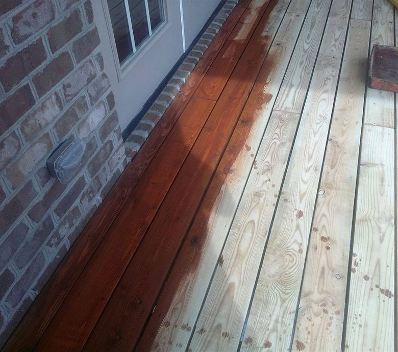 A wooden deck with a brick wall in the background