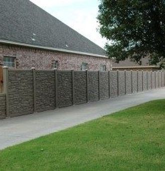 A brick house with a stone fence in front of it.