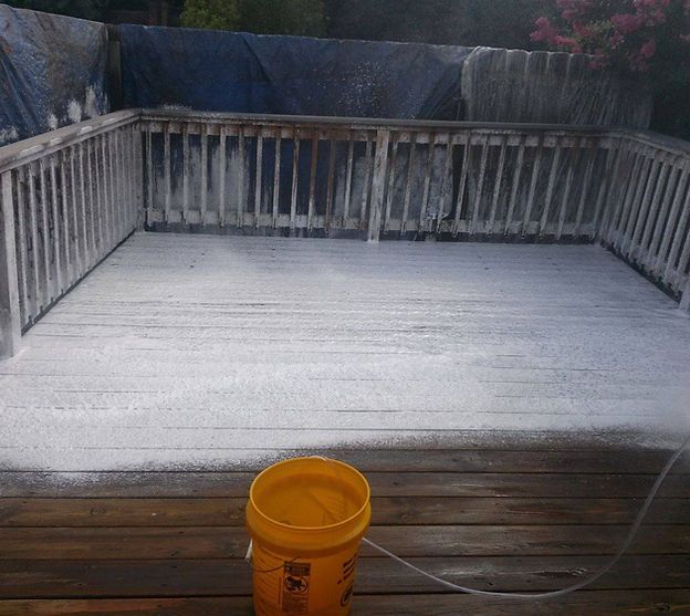 A yellow bucket is sitting on a wooden deck.