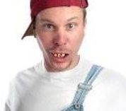 A man wearing overalls and a baseball cap is making a funny face.