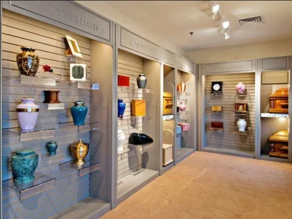 Display of colorful cremation urns in a funeral home showroom, featuring various shapes and styles.
