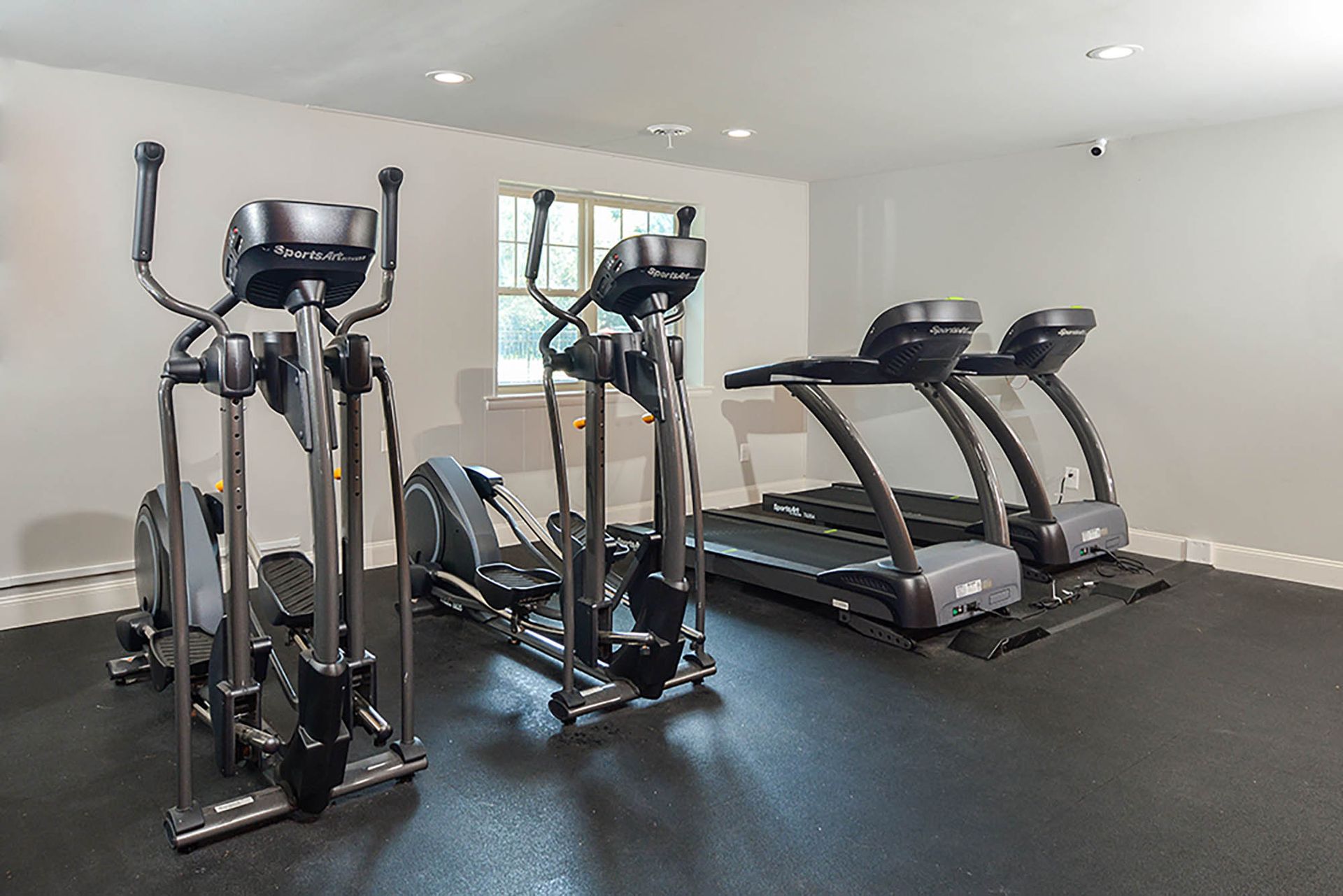 Small indoor gym with cardio machines, including elliptical trainers and treadmills.