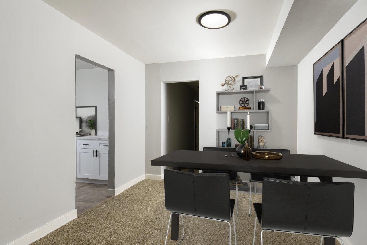 Dining area with a dark rectangular table, four black chairs, and a shelving unit in a modern apartment.