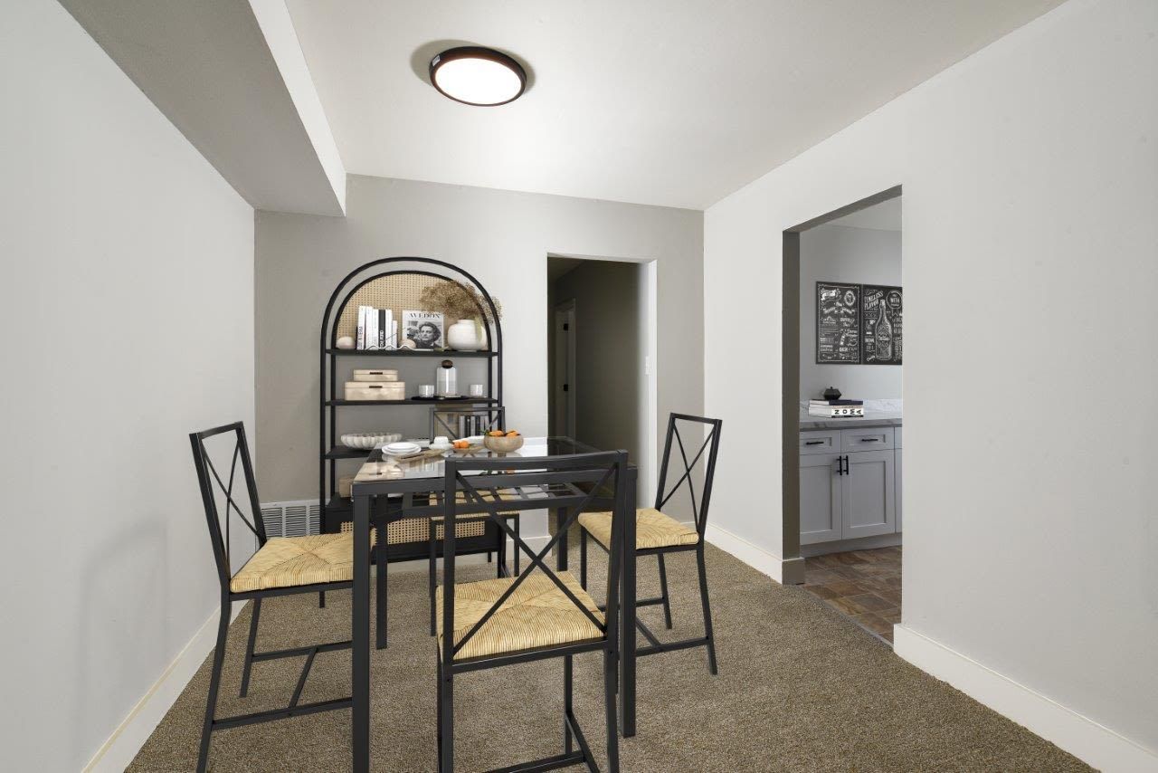 Dining area with a glass-top table, four metal-framed chairs, and a shelving unit.