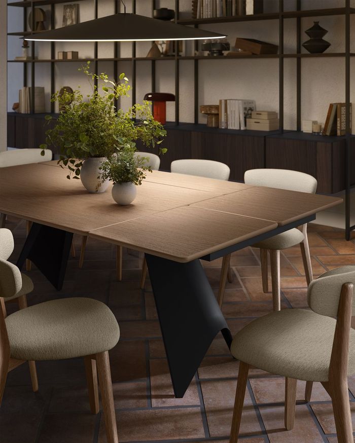 In una stanza moderna, un tavolo da pranzo con piano texturizzato e gambe geometriche nere, circondato da sedie color crema.