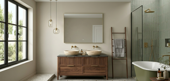 Un bagno moderno con doppio lavabo in legno, pareti beige, un grande specchio, due lampade a sospensione e una vasca da bagno verde.