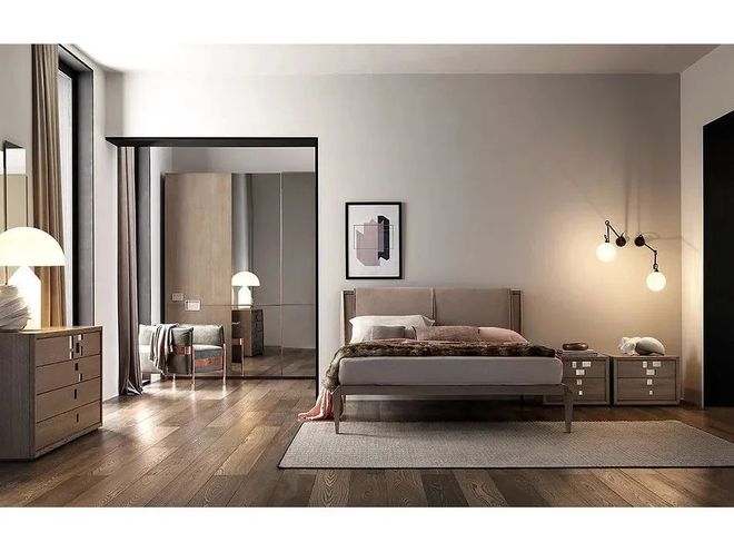 Camera da letto moderna con letto, cassettiere in legno, ante dell'armadio riflettenti e illuminazione a parete calda su pareti grigio chiaro.