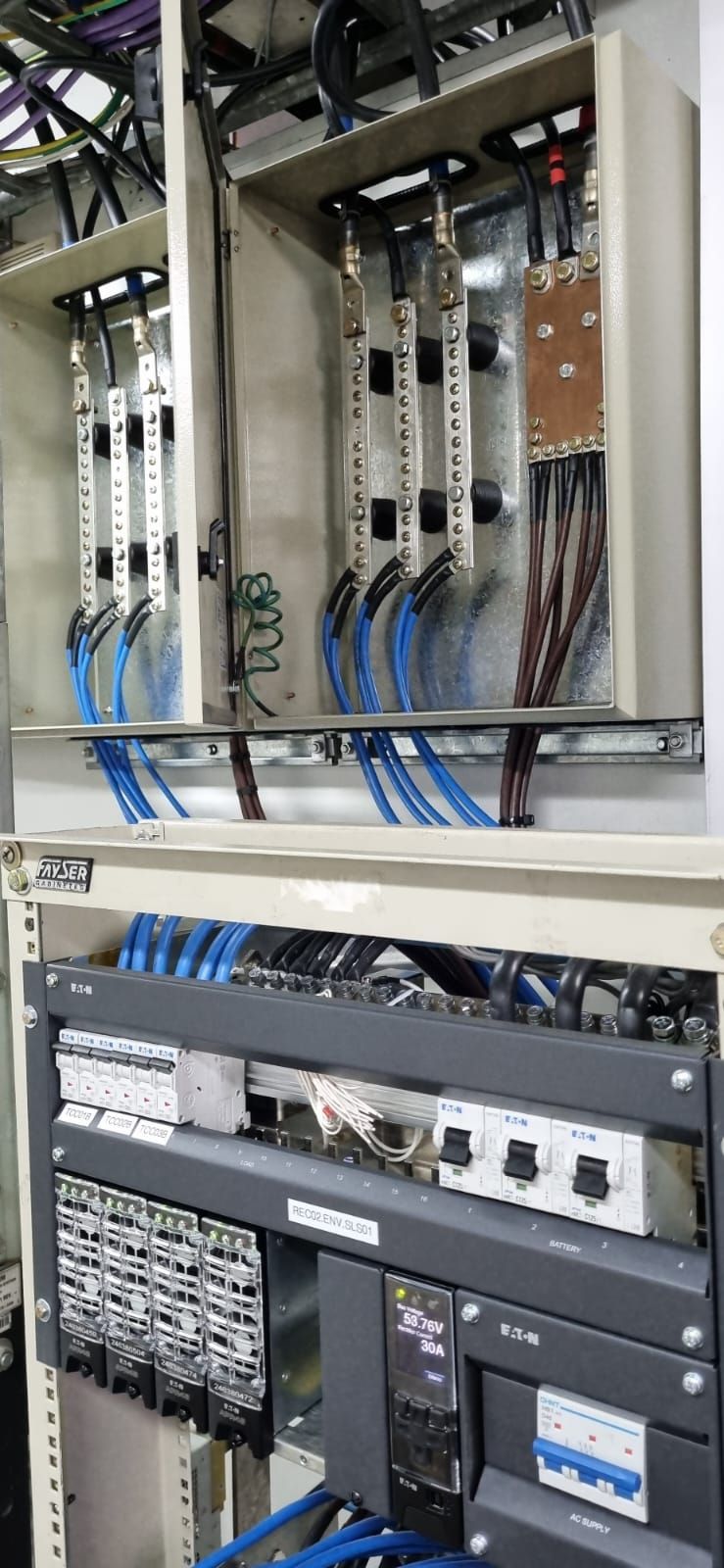 Panel de control eléctrico con cableado, disyuntores y módulos de circuito dentro de un gabinete metálico.