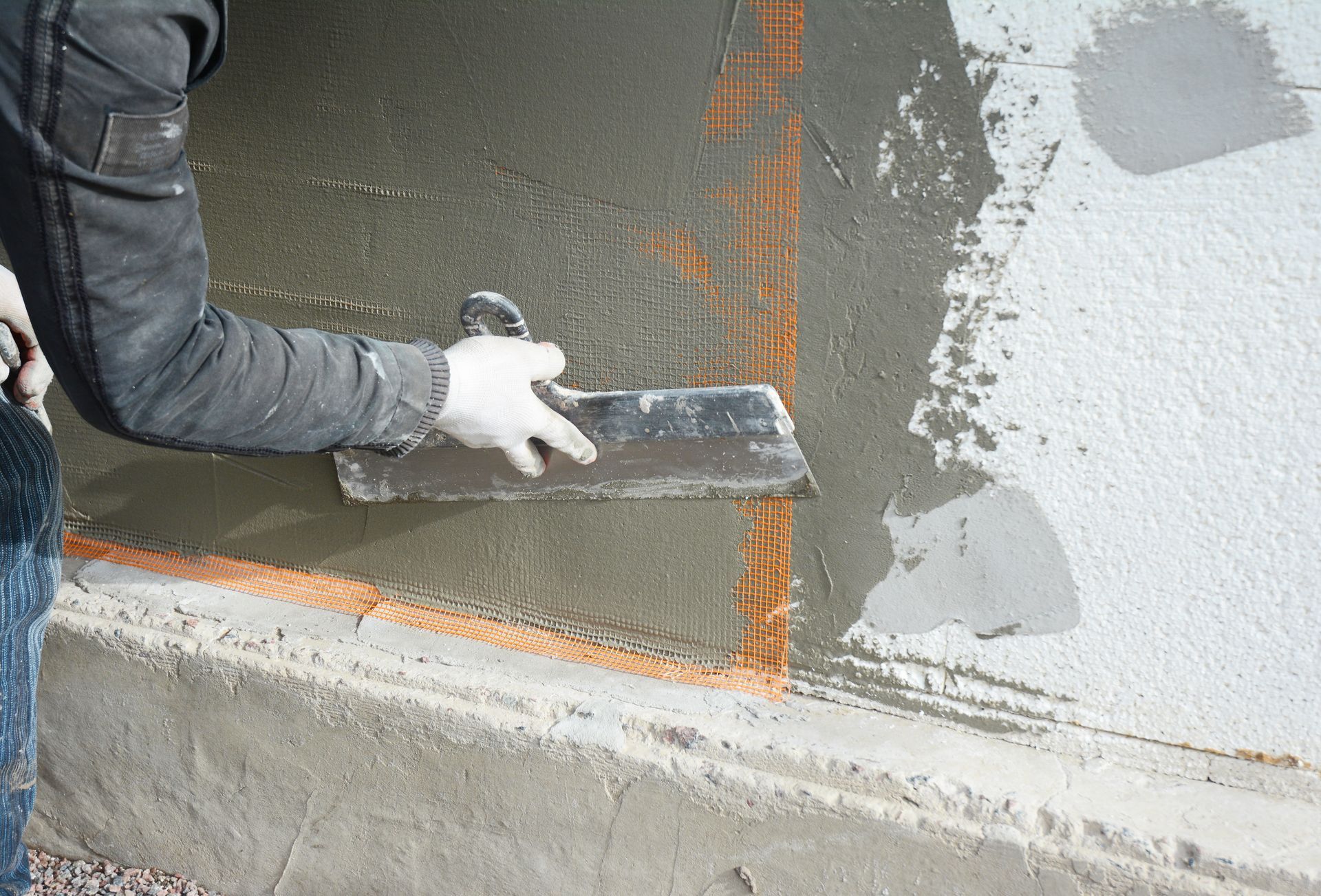 Person using a trowel to apply cement to a wall