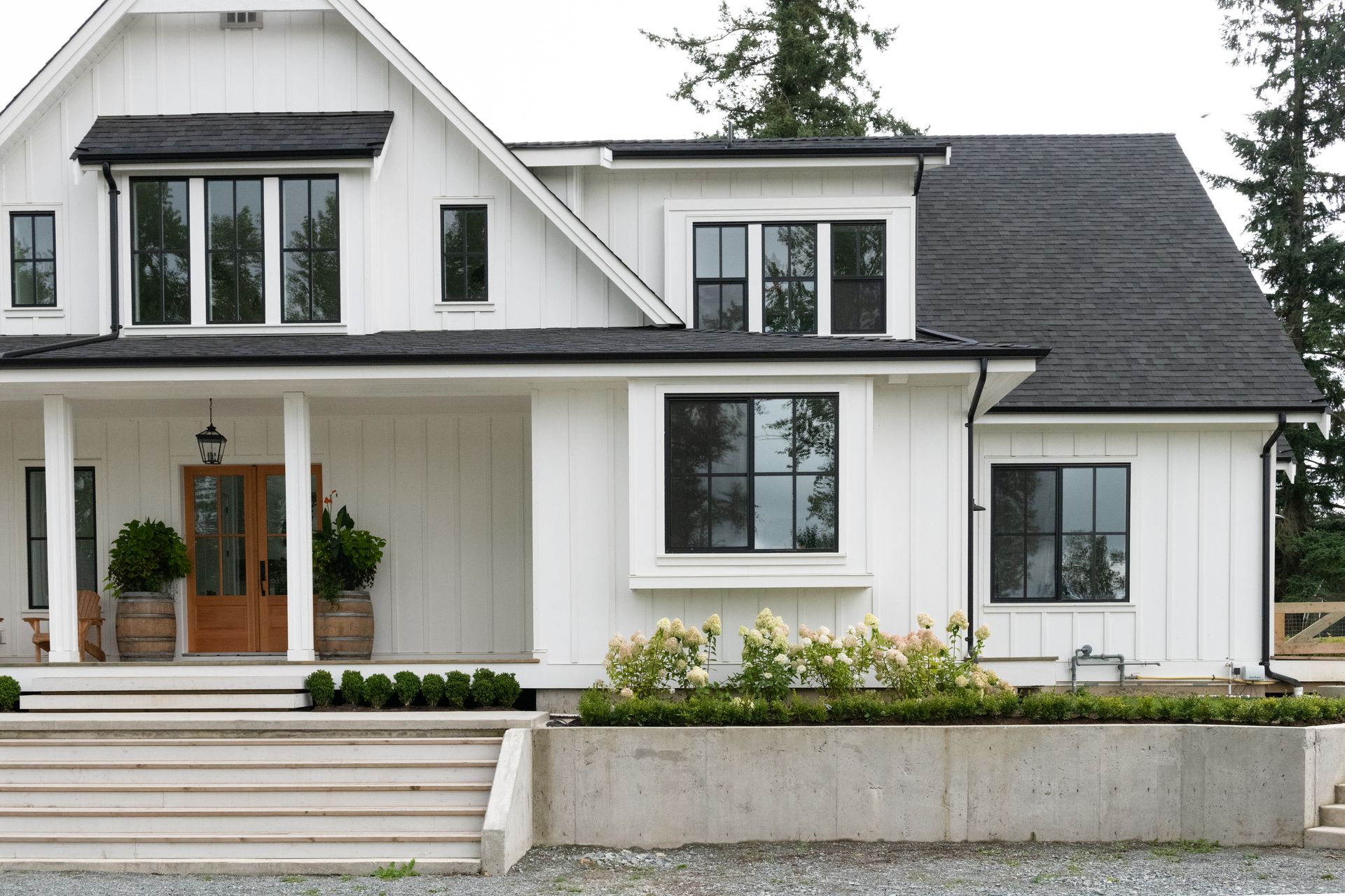White farmhouse with black-framed windows and a brown front door