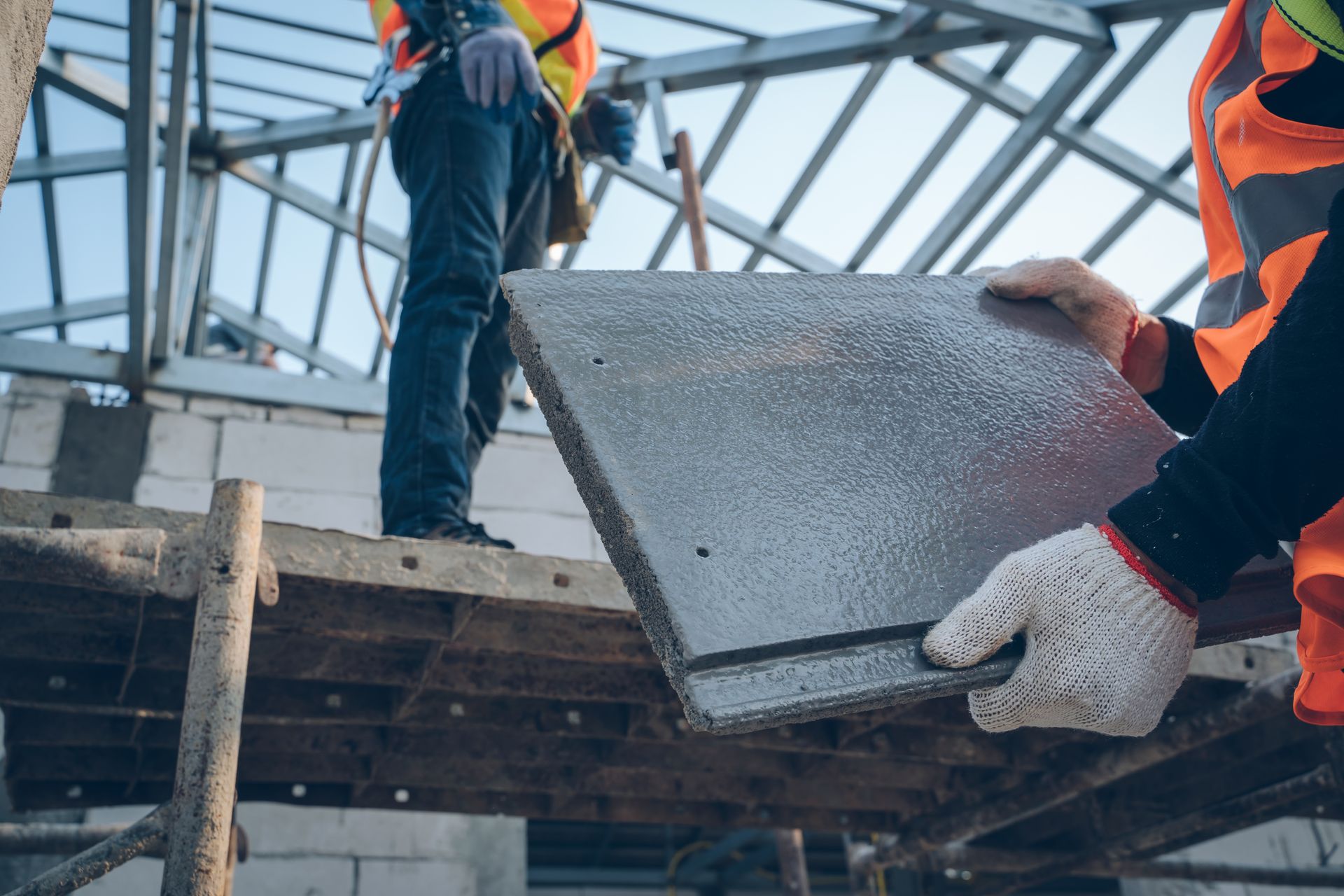 Construction worker installing a roof tile on a building under construction