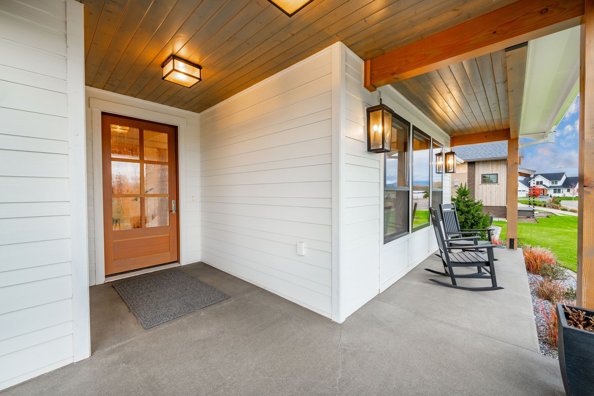 A covered porch with a brown door