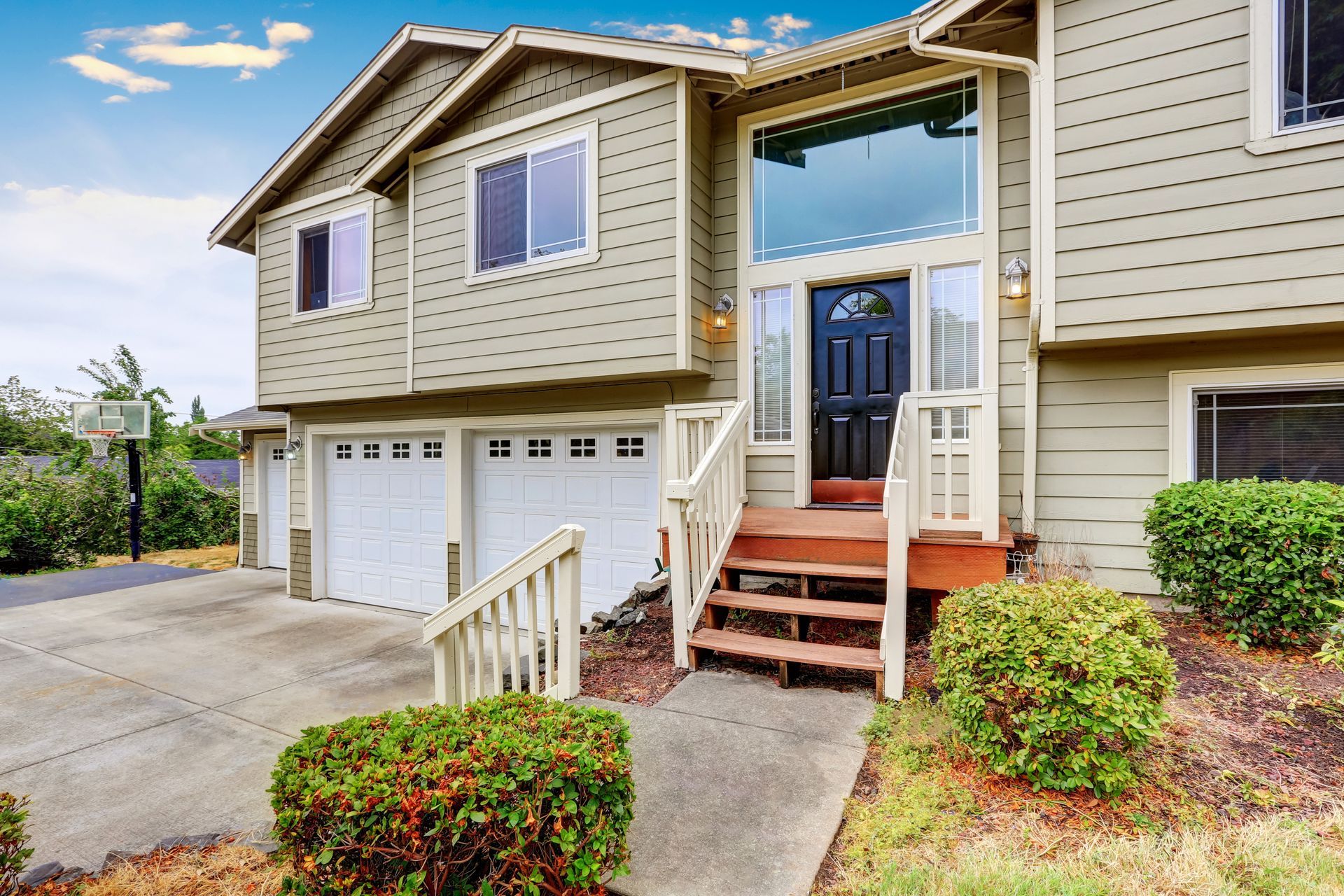 Two-story beige house with white garage doors
