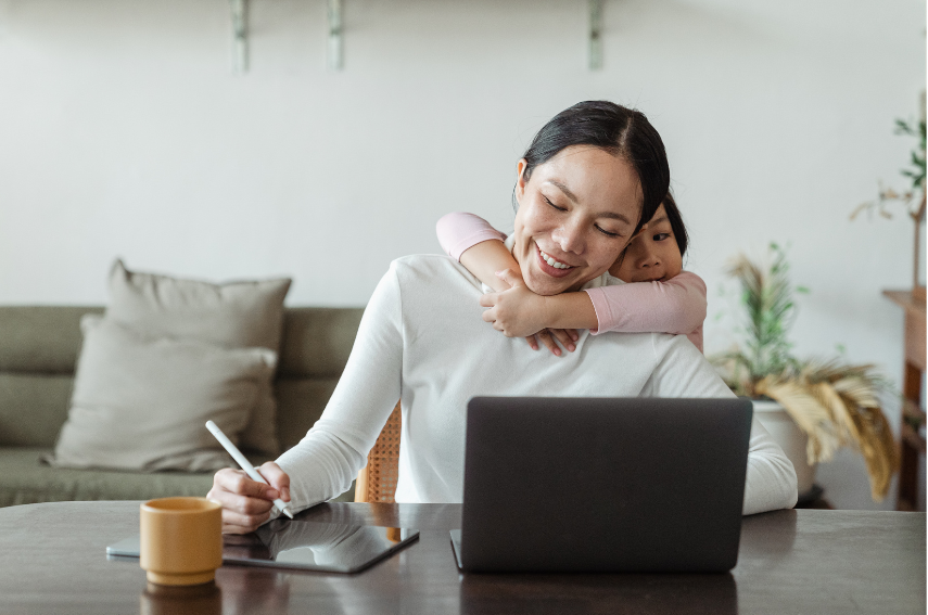 a woman is holding a baby while using a laptop computer .