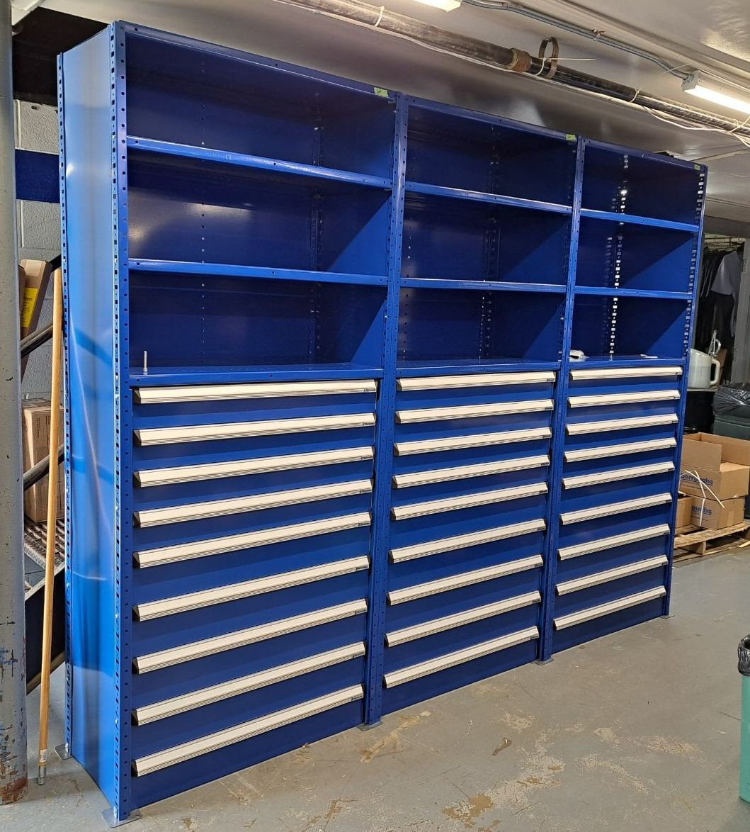 A row of blue shelves with drawers in a warehouse.