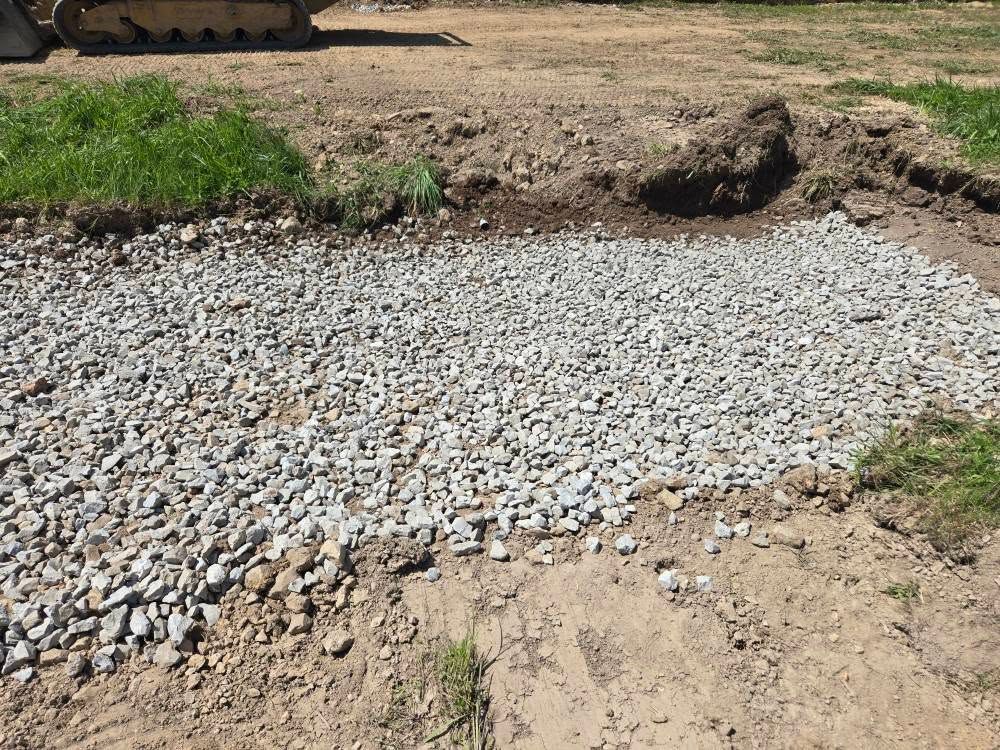 Gravel path being constructed, bordered by dirt and grass; daytime.