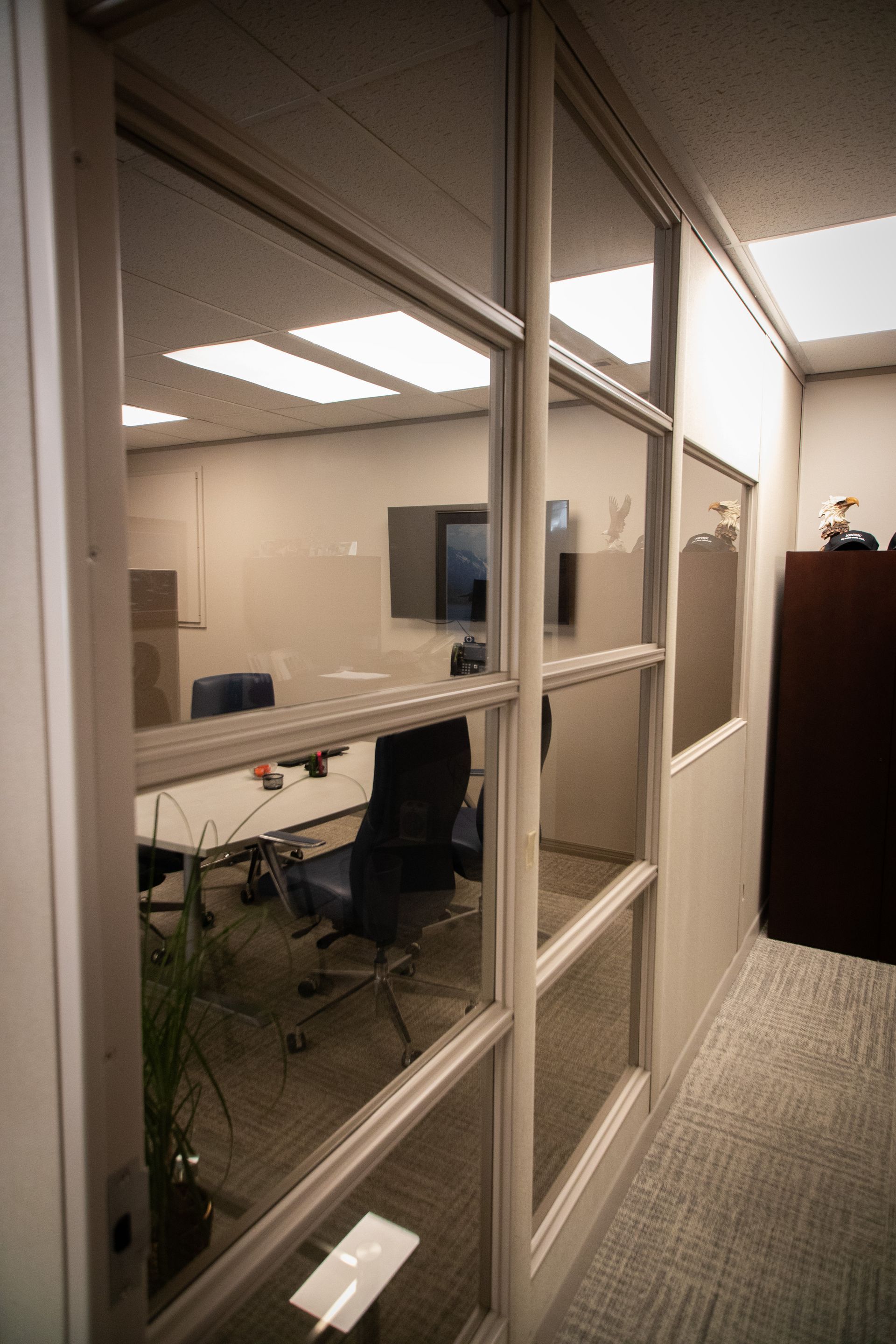 A conference room with a glass wall and a table and chairs.
