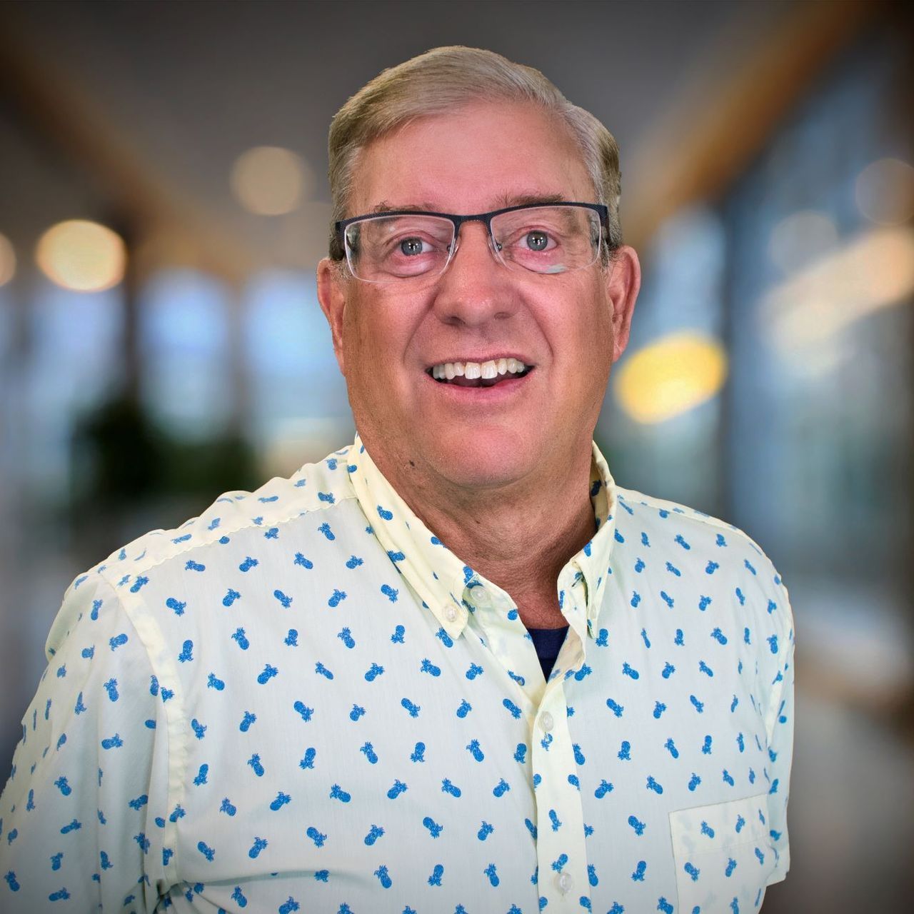 A man wearing glasses and a white shirt is smiling for the camera