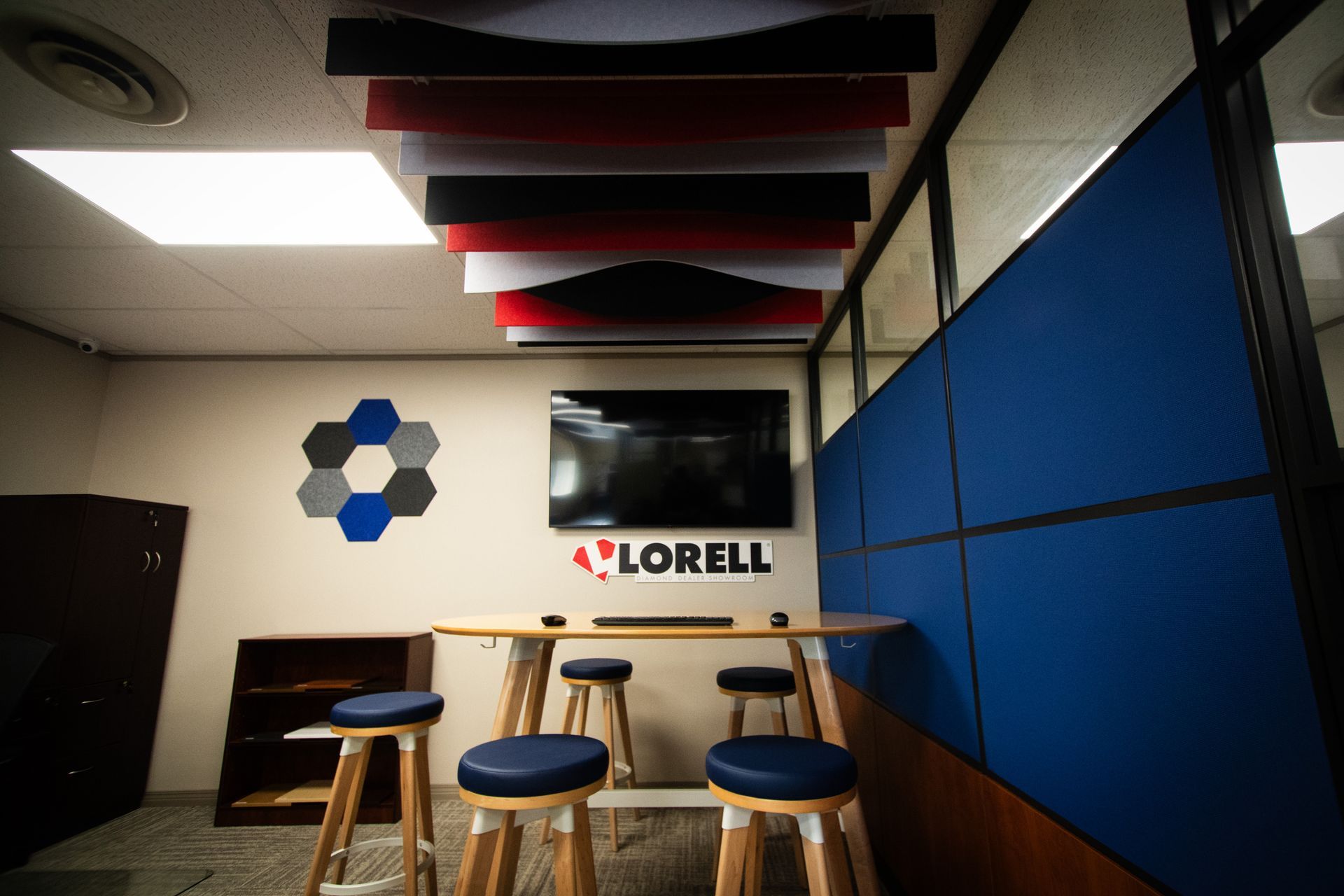 A room with a table and stools and a television on the wall.