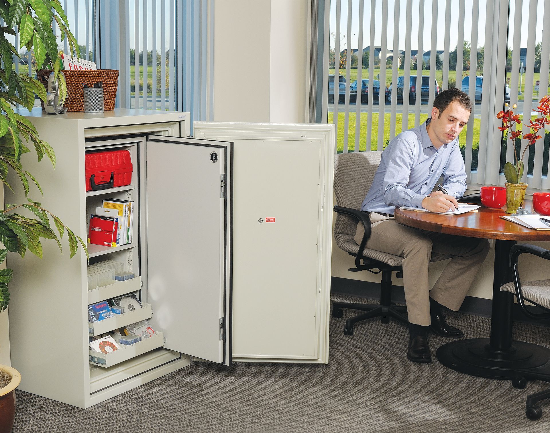 A man is sitting at a table in front of a safe