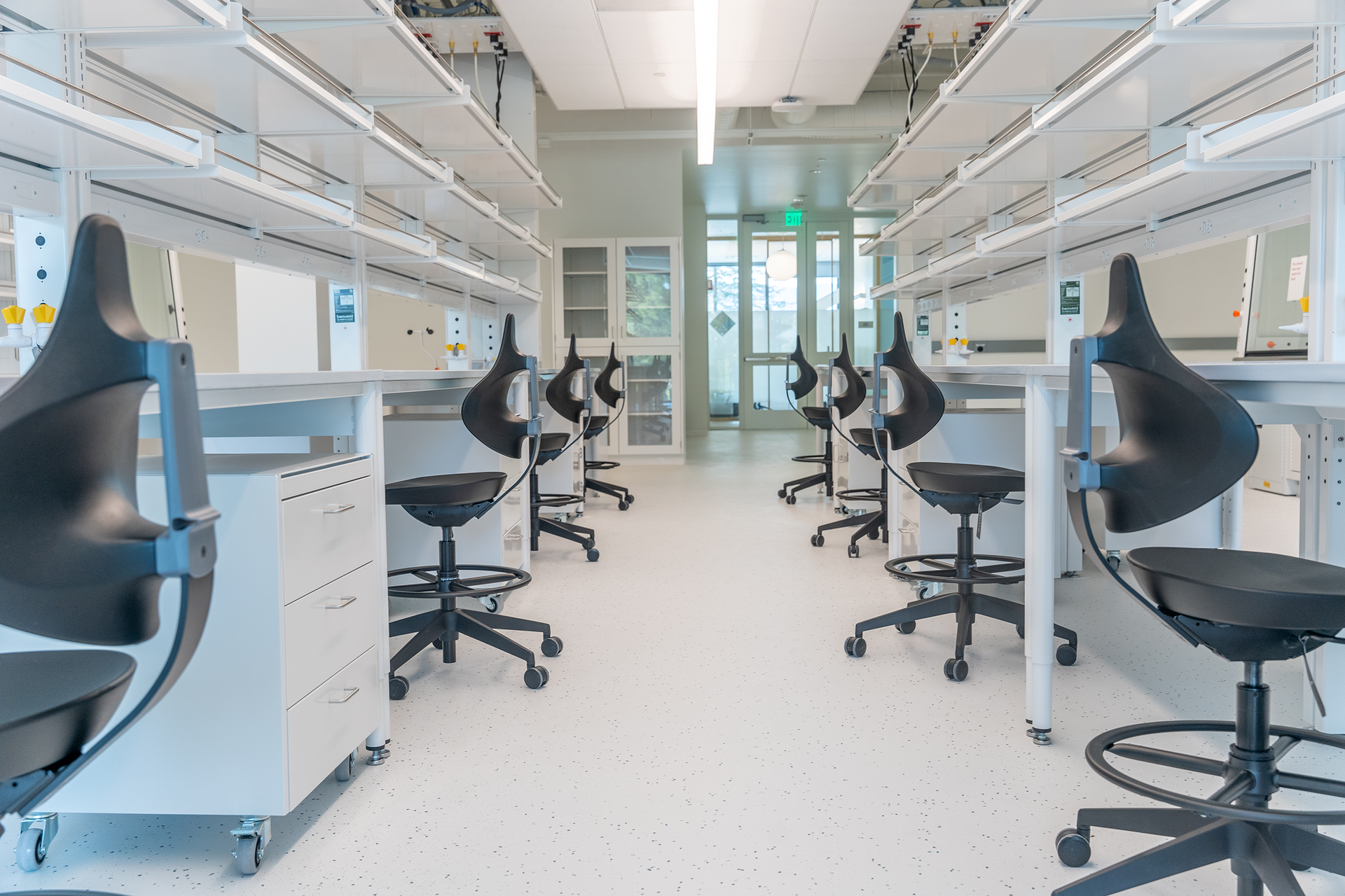 A row of black chairs are lined up in a lab.