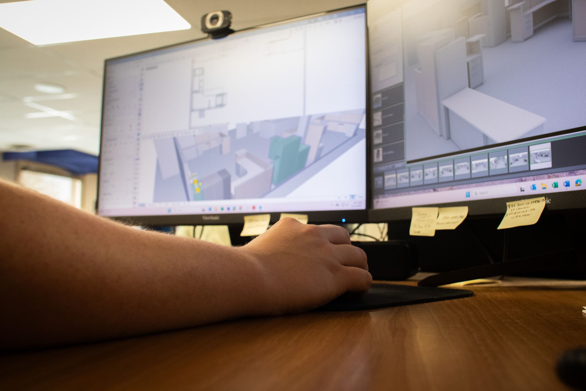 A person is sitting at a desk in front of two computer monitors.