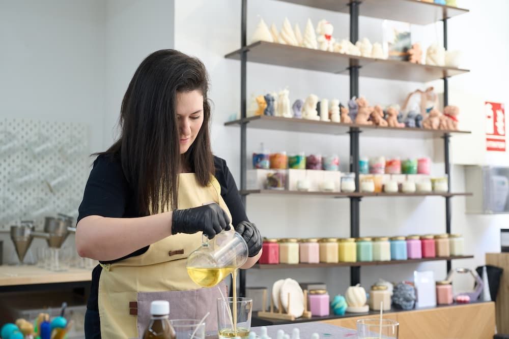 Woman crafting products with retail shelving displaying finished goods, relevant to commercial storage solutions and small business inventory.