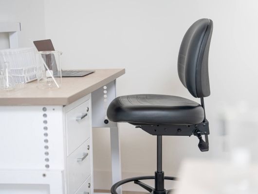 A black office chair is sitting in front of a desk with a laptop on it.