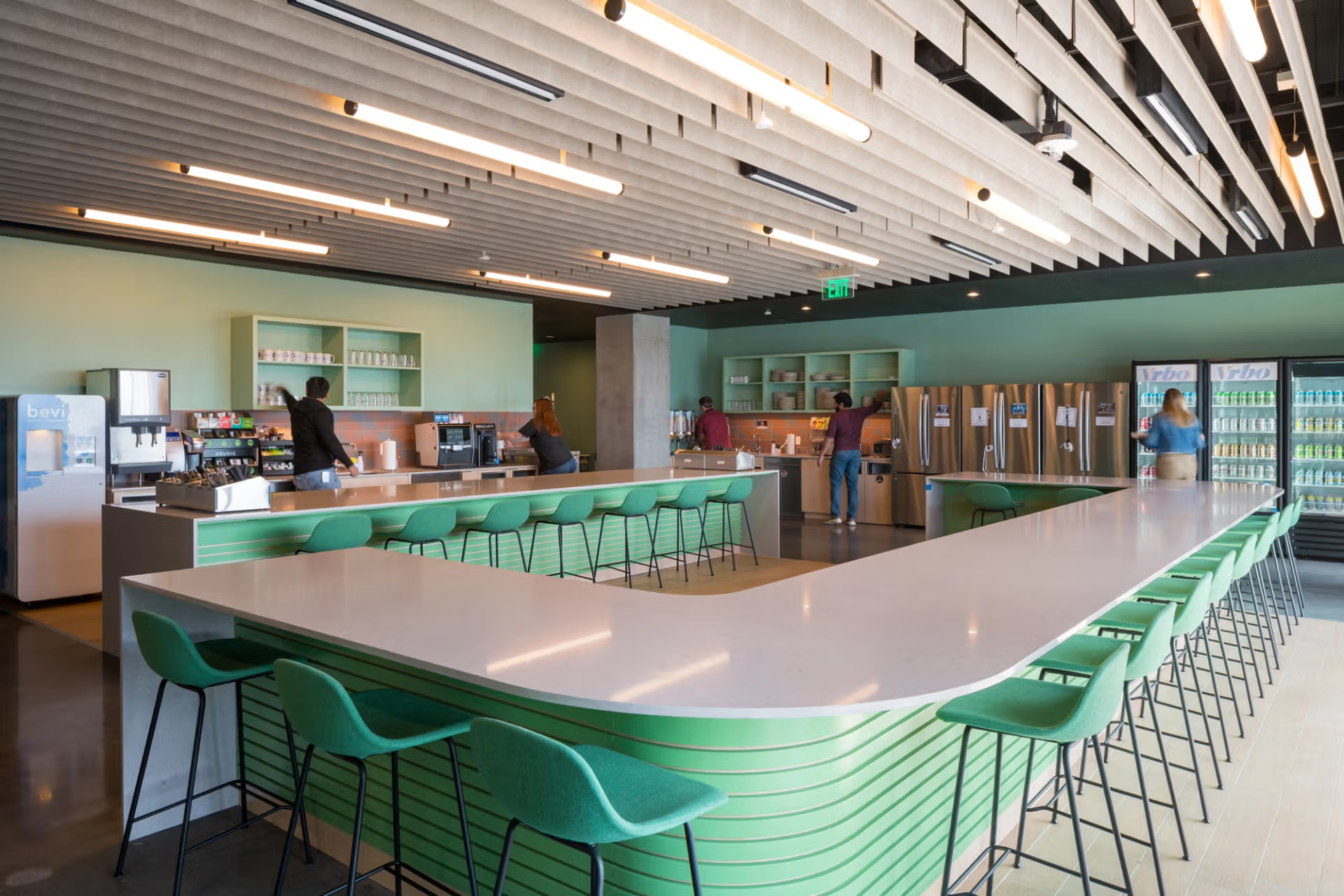 A kitchen with a long green counter and green chairs.