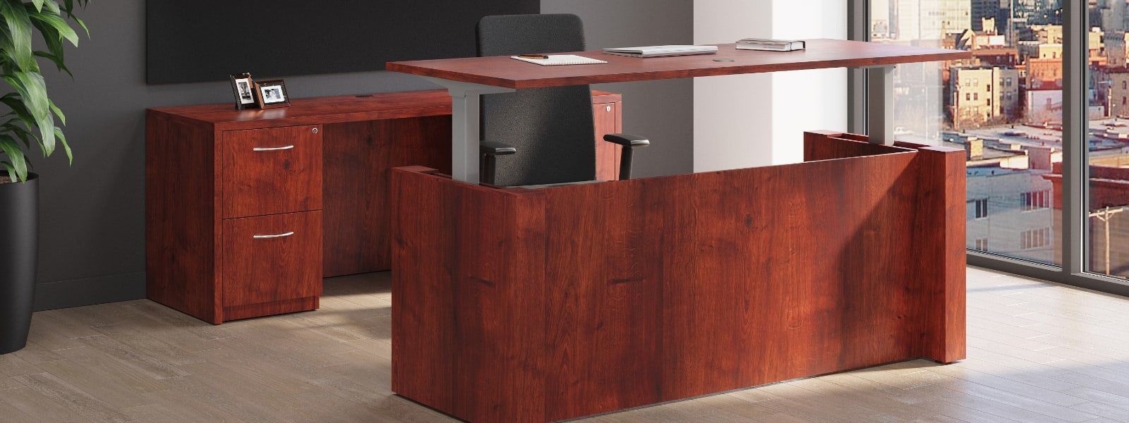 A wooden desk is sitting in a room next to a window.