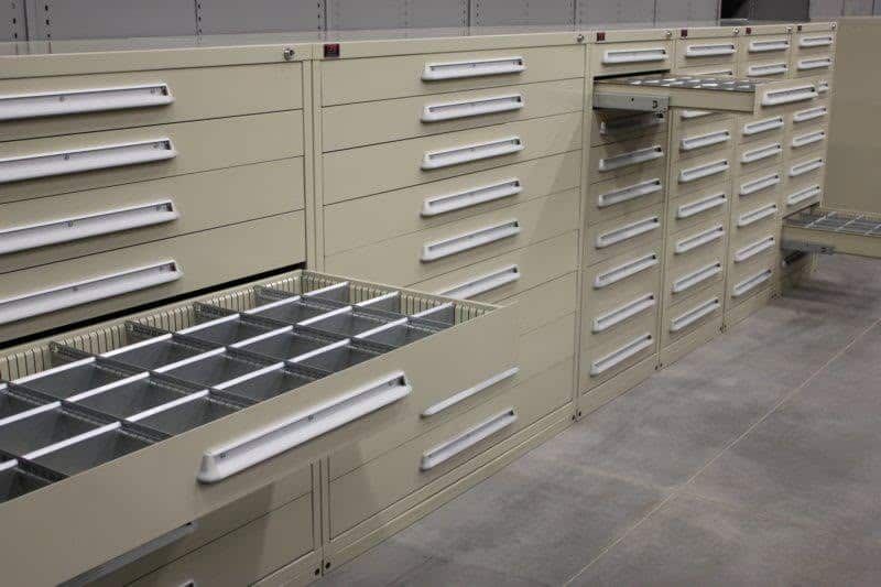 A row of drawers in a warehouse with one drawer open.