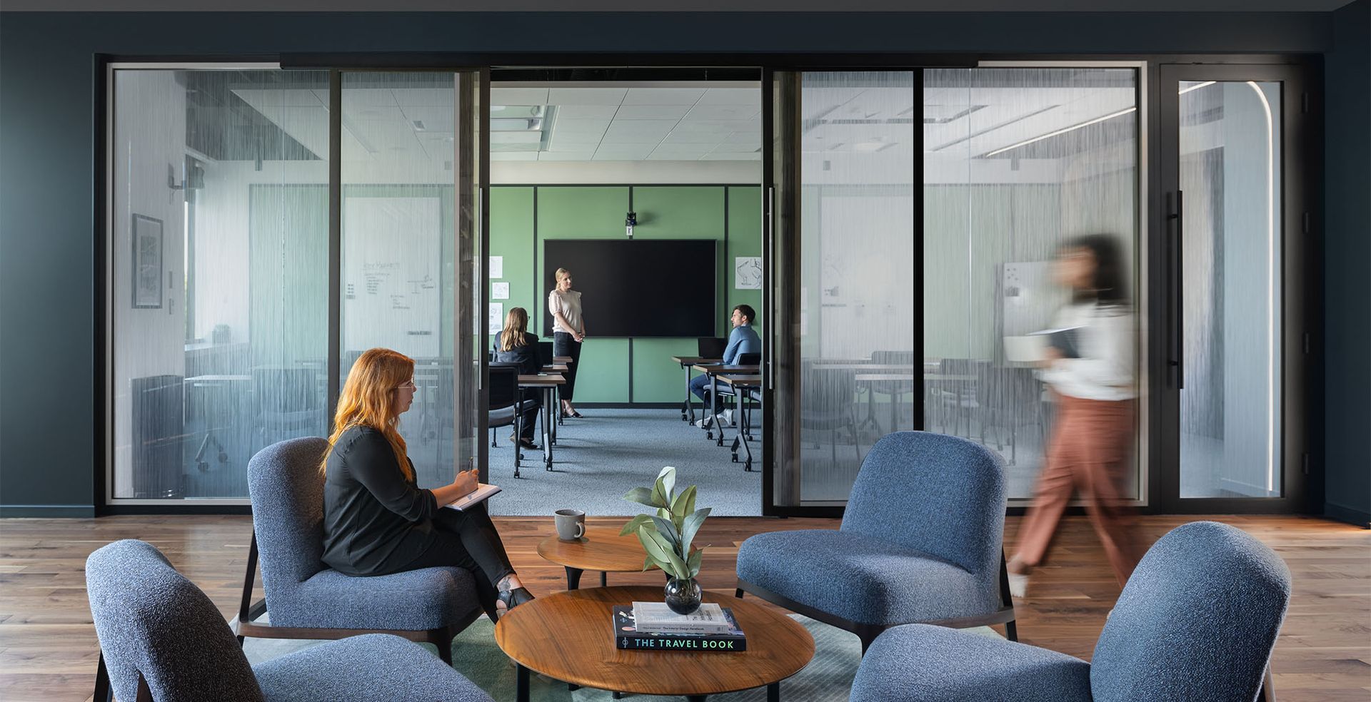 A woman is sitting in a chair in a room with chairs and tables.