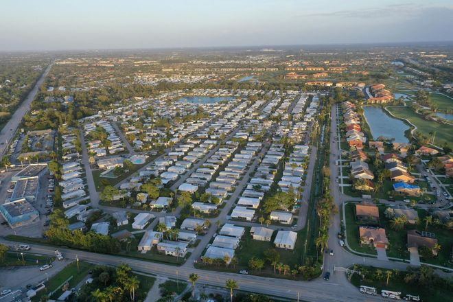 An aerial view of a dense residential neighborhood with uniform homes and small lakes in a flat, suburban landscape.
