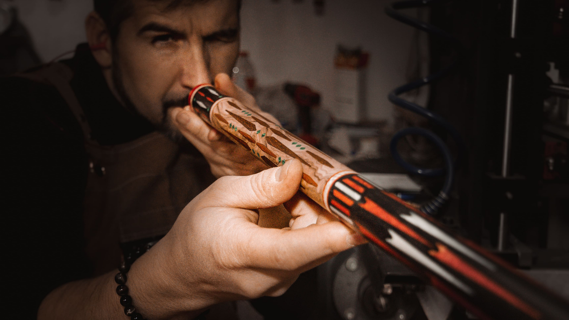 Man inspecteert een afgewerkte, gestreepte keu en houdt deze voor zijn gezicht. Werkplaatsomgeving.