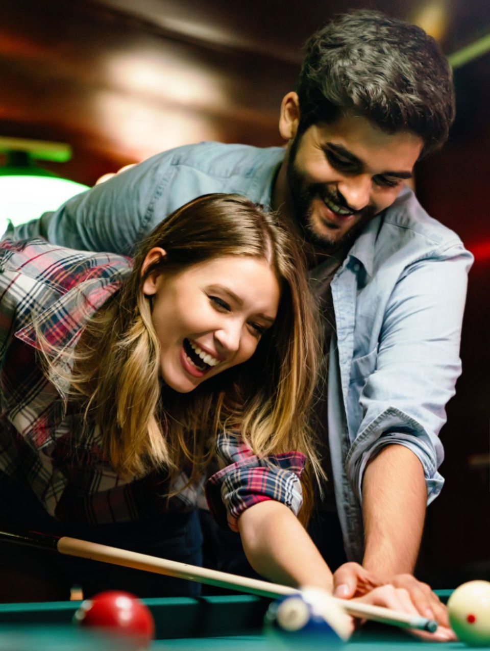 Een man en een vrouw spelen samen pool en lachen.