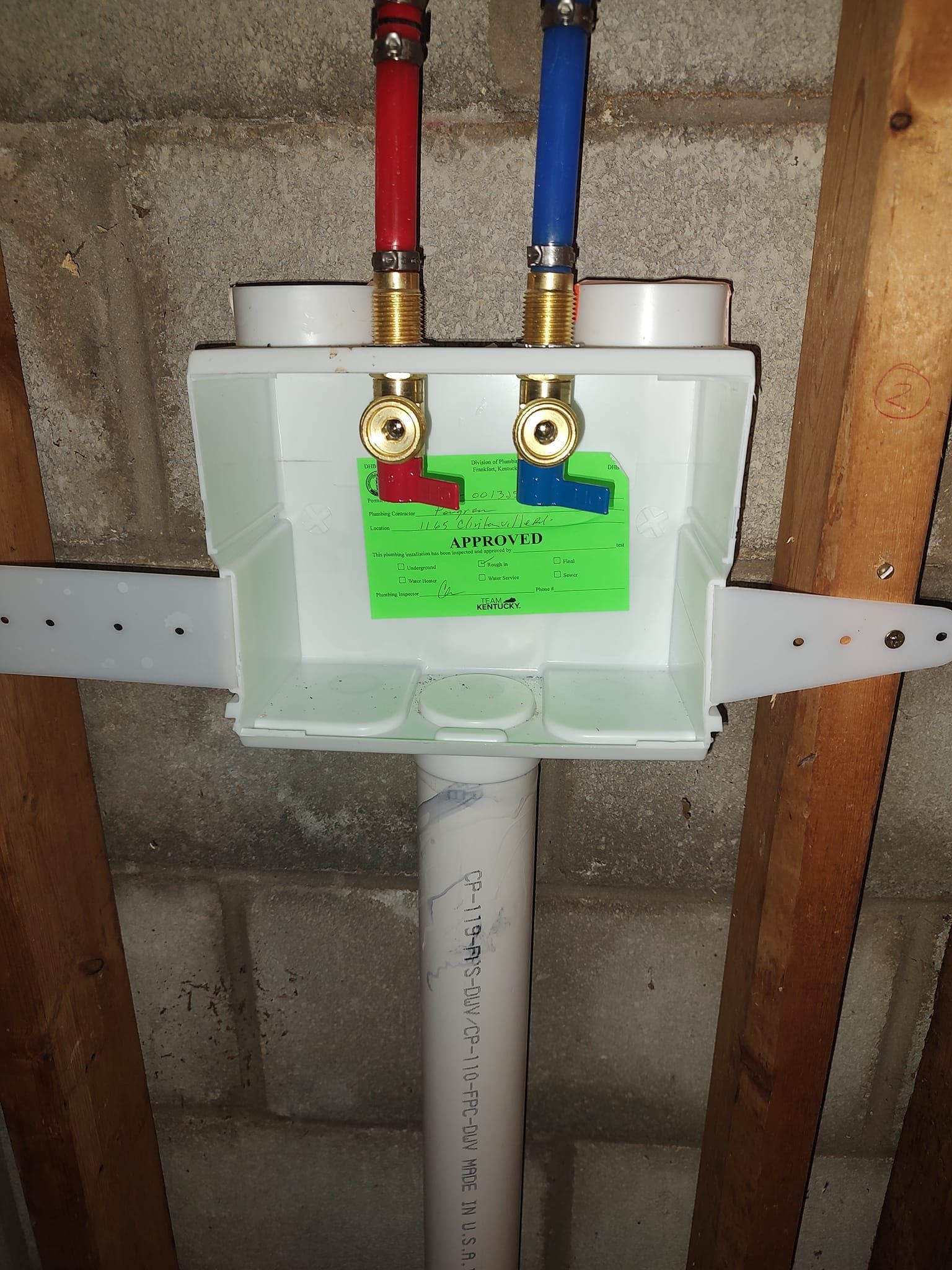 Laundry water supply box with red/blue PEX pipes, shutoff valves, and drain pipe.