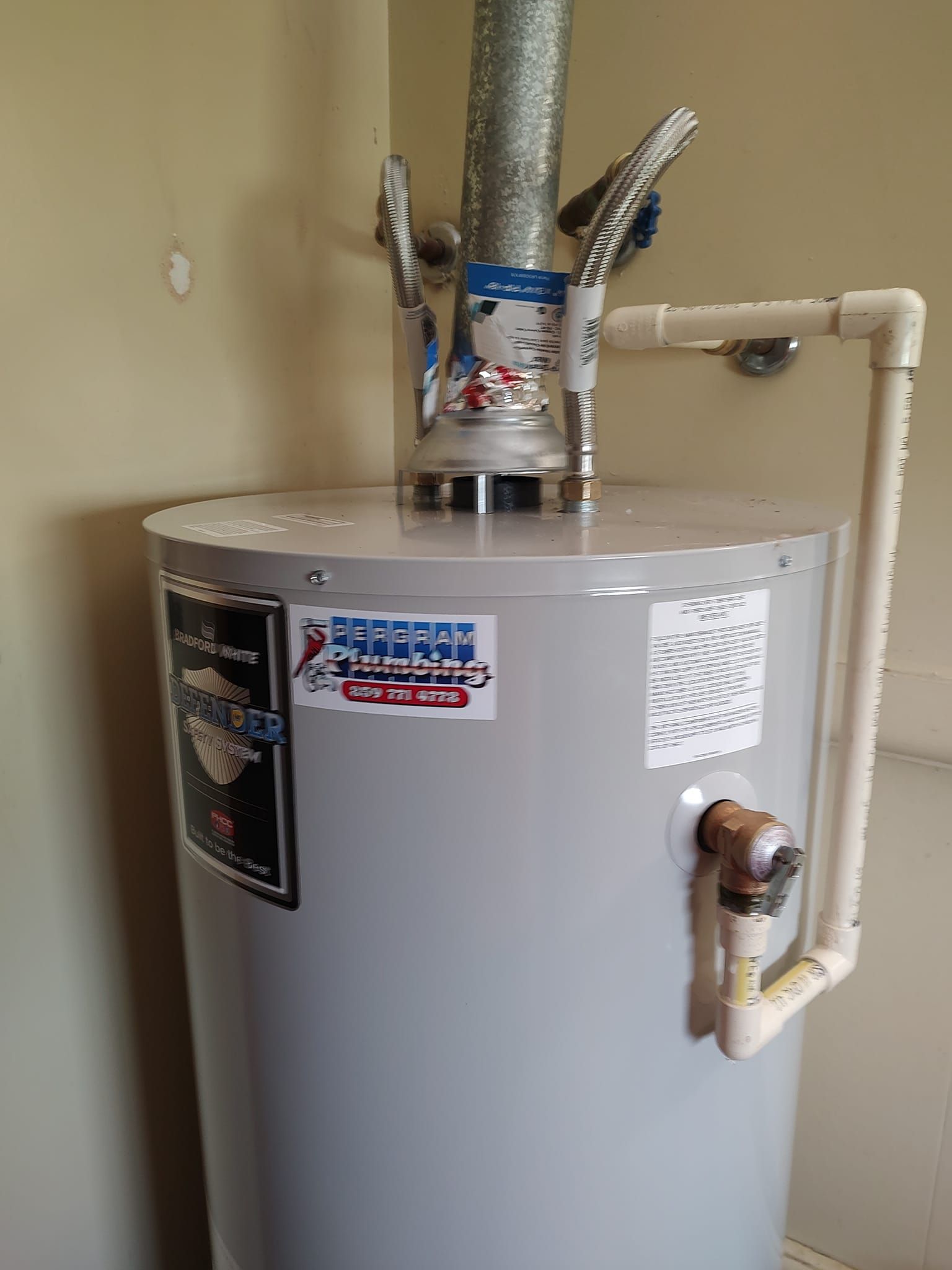 White Marey tankless water heater mounted on a wall with red, blue, and black pipes.